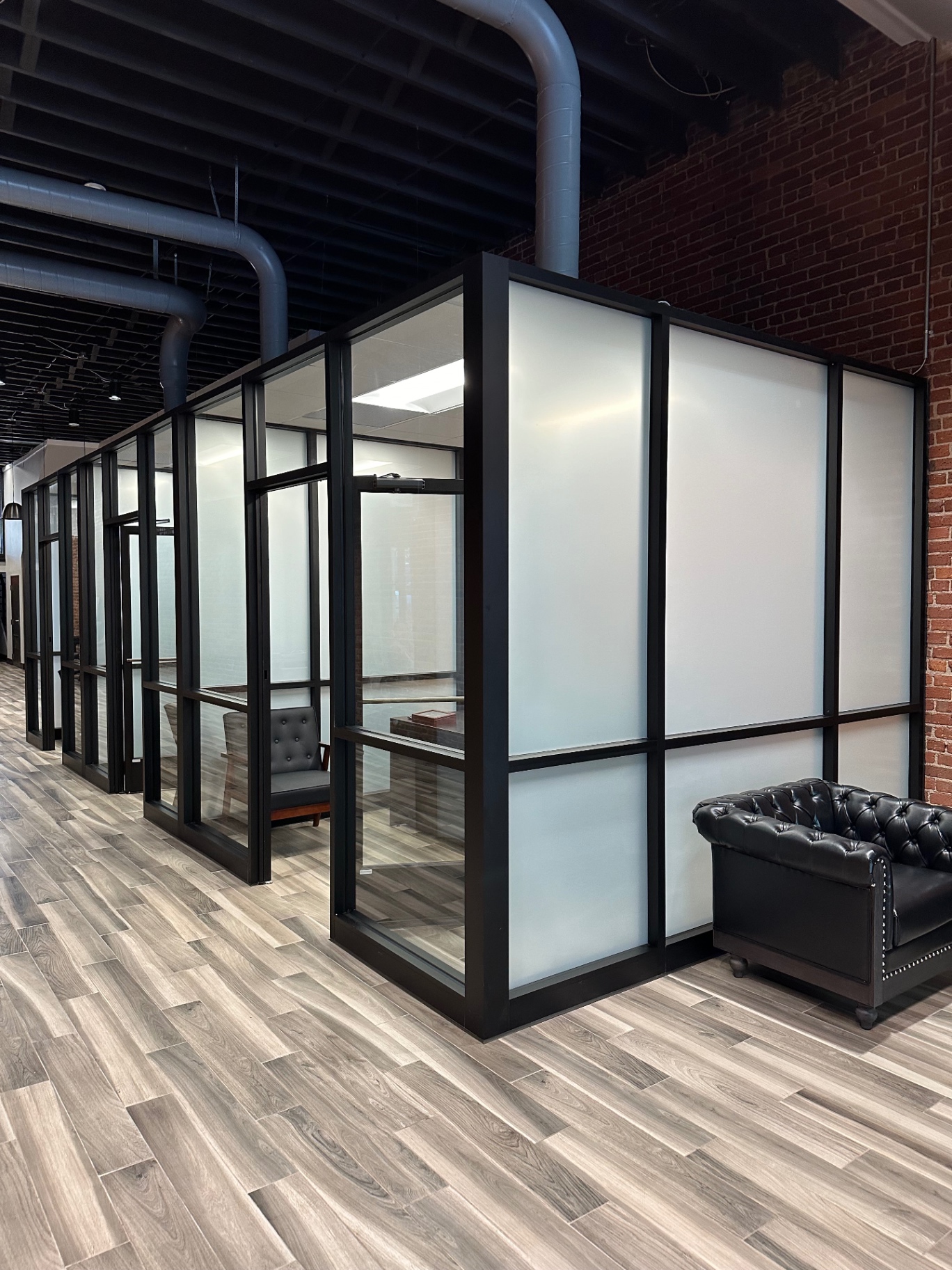 Office conference rooms with frosted privacy film on black-framed glass partitions