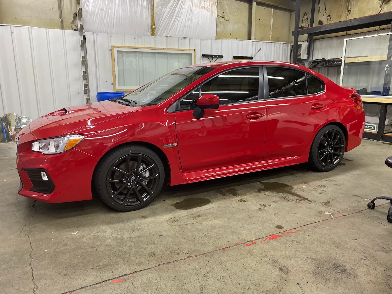 Red Subaru WRX with completed window tint inside the install bay