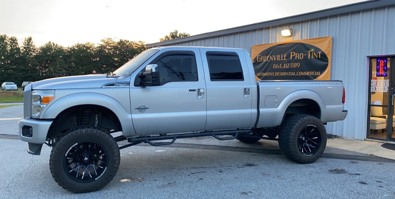 Lifted silver Ford F-350 with completed window tint outside the Greenville Pro Tint shop
