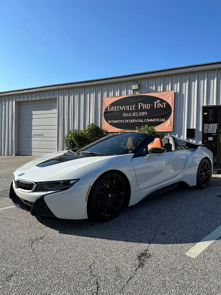 White BMW i8 Roadster with tinted glass in front of the Greenville Pro Tint shop