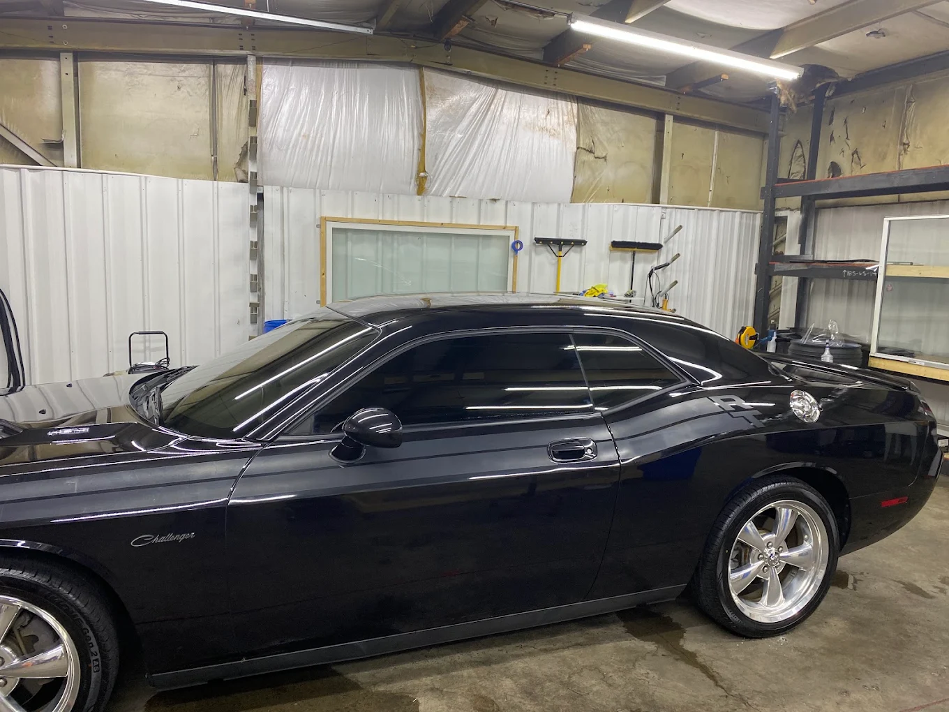 Black Dodge Challenger with completed window tint inside the install bay