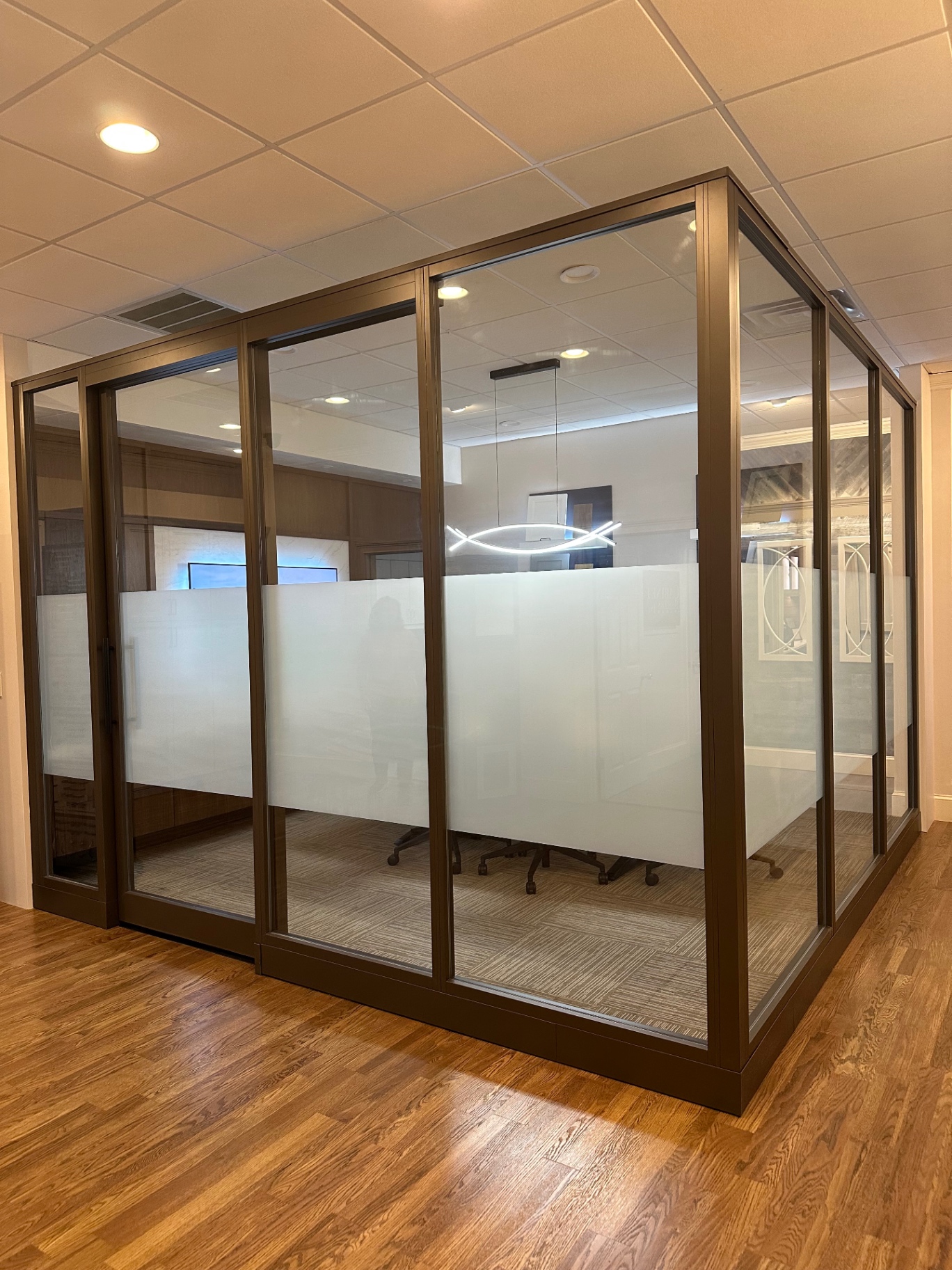 Bronze-framed glass office wall with a frosted privacy band